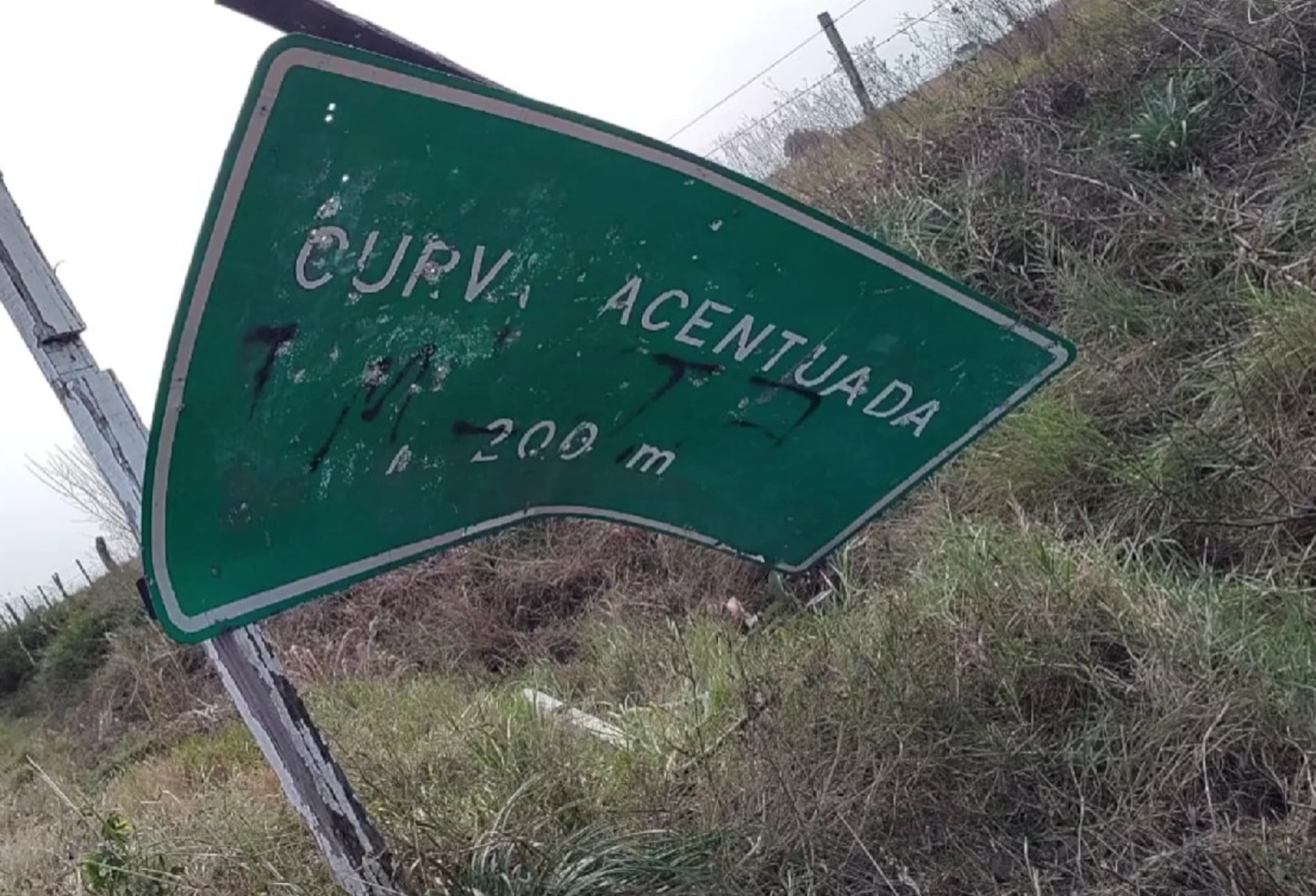 A placa de sinalização que existe no local está caída e pichada
